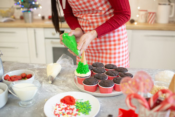 Obraz na płótnie Canvas Girl prepares cupcakes in the form of Christmas trees.