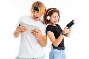 Stylish caucasian blonde man and young woman play phone games and listen to music isolated on white background