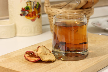 Compote of dried fruits in a glass glass on a wooden board on a background of wicker basket