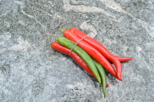 Rote und gr&uuml;ne Peperoncini auf Granittisch