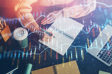 Forex graph on hand taking notes background. Concept of research. Double exposure