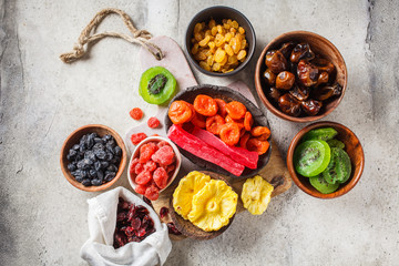 Variety of dried fruits in bowls. Dates, raisins, dried apricots and exotic dried pineapple, papaya and kiwi, top view.