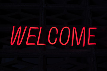 Red color neon glowing sign text welcome on black background. Made from luminescent illuminated lamp