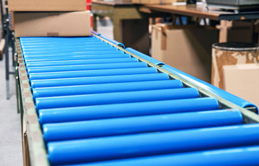 Blick über ein Rollband in einem Betrieb mit Kartons m Hintergrund - extra viel Copyspace im...