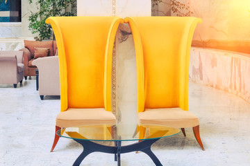 Two high-backed chairs in the hotel lobby. Furniture with a glass table in the interior on the...