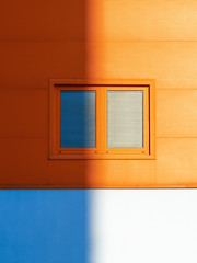 Obraz na płótnie Canvas Window with blinds and an orange wall half in shadow.