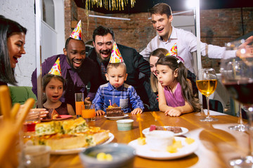 Portrait of happy multiethnic family celebrating a birthday at home. Big family eating cake and drinking wine while greeting and having fun children. Celebration, family, party, home concept.