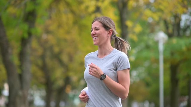 Slow motion shot of a girl jogging in a park. The athlete is engaged in training. Fitness outdoors. Sport