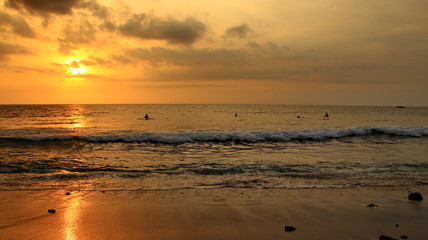 Fototapeta na wymiar Documentation of surfers in action at dusk with a golden color and dark, unfocused and dark on the beach of Senggigi Lombok, West Nusa Tenggara Indonesia, 27 November 2019