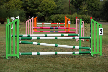 Obraz na płótnie Canvas Colorful barriers on the ground for jumping horses and riders at riding school as a background.Obstacles for horses in a riding school