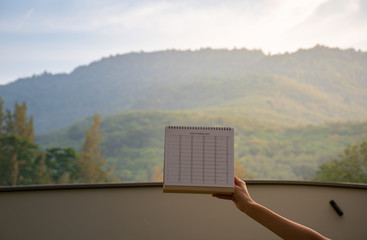 Asian women raises up the New year 2020 calendar and planner among the hill valley.