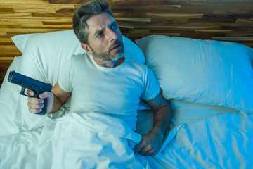 night edgy portrait of young stressed and paranoid American man lying on bed unable to sleep...