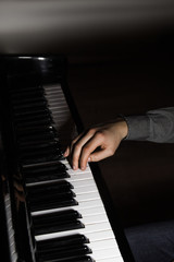 Fototapeta na wymiar one male hand on the piano. The palm lies on the keys and plays the keyboard instrument in the music school. student learns to play. hands pianist. black dark background.