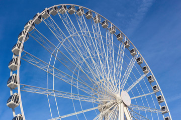White Ferris or Big wheel against a blue sky.  Fairground or Carnival ride
