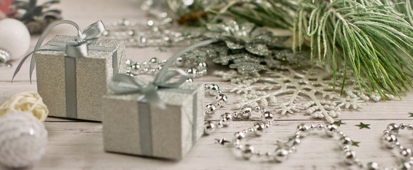 Christmas light gray background on wooden boards with tinsel, toys, fir branches and gifts.