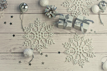 Christmas light gray background on wooden boards with tinsel, toys, silver stars, snowflakes and gifts.