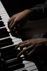 Fototapeta na wymiar two male hands on the piano. palms lie on the keys and play the keyboard instrument in the music school. student learns to play. hands pianist. black dark background.