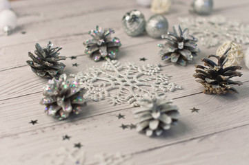 Christmas light gray background on whitewashed wooden boards with toys, silver snowflakes, fir cones and gifts