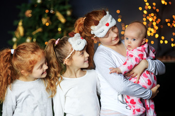 Four girls children cuddle. Sisters in pajamas. The concept of Merry Christmas, holidays, family and gifts.