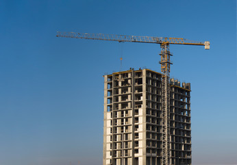 Tower cranes constructing a new residential building at a construction site against blue sky. Renovation program, development, concept of the buildings industry.