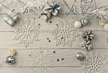 Christmas light gray background on whitewashed wooden boards with toys, silver snowflakes, fir cones and gifts
