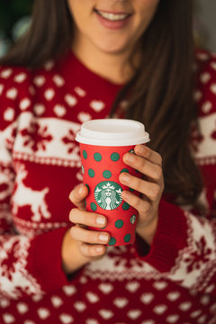 New York, USA - December 9, 2019: Woman Wearing a Christmas Sweater Holding a Christmas Holiday Cup Starbucks During 2019 Christmas Holiday.