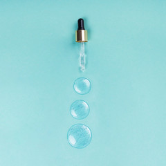 Medical dropper and drops of hyaluron on a blue background.
