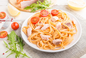 Semolina pasta with salmon and salmon steak on a white wooden background. Side view, selective focus.