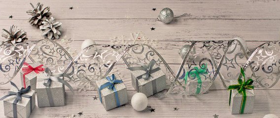 Christmas light gray background on wooden boards with tinsel, toys, silver stars, snowflakes and gifts.
