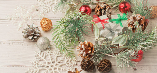 Christmas light gray background on whitewashed wooden boards with green spruce wreath, toys, silver snowflakes and gifts