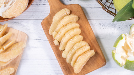 Fresh peeled pomelo, pummelo, grapefruit, shaddock on bright wooden background. Autumn seasonal fruit, top view, flat lay, tabletop shot.