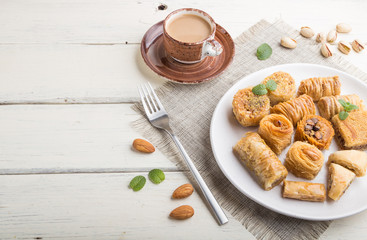 traditional arabic sweets (kunafa, baklava)  and a cup of coffee on a white wooden background. side view, copy space.
