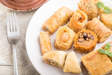 traditional arabic sweets (kunafa, baklava)  and a cup of coffee on a white wooden background. side view, selective focus.