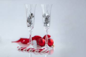 White gift box with red ribbon sweets, champange glasses and decorations on white background. Christmas and New Year holidays concept.