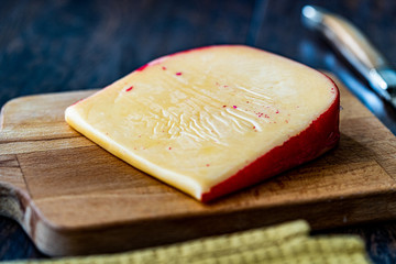 Hard Dutch Gouda Cheese, Close-up on Wooden Board with Knife.