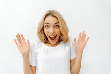 girl shows different emotions. a woman in a white T-shirt on a white background is sincerely surprised. copy space