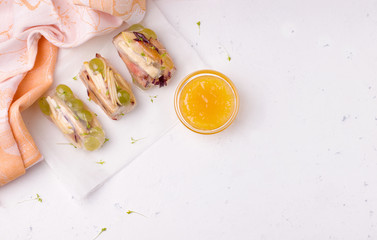 spring rolls of fruits on rice paper on a white background, next to orange jam. have copy space