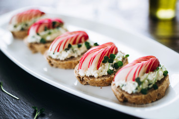 Canapes with cheese and garlic and radish, sprinkled with sprouts of young beans. Snack at the restaurant for alcohol