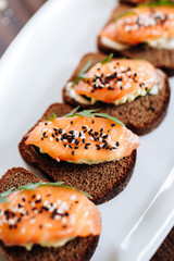 Red fish on rye bread with arugula and sesame. Fish rope. Restaurant appetizer with red fish