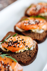 Red fish on rye bread with arugula and sesame. Fish rope. Restaurant appetizer with red fish
