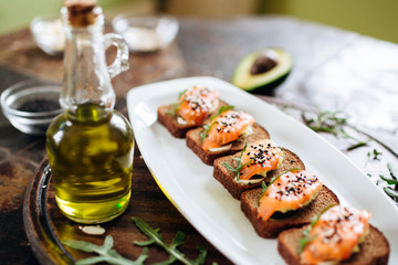 Red fish on rye bread with arugula and sesame. Fish rope. Restaurant appetizer with red fish