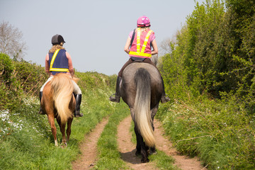 Two riders ridin into distance along a country track in rural Shropshire, both wearing correct...