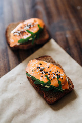 Red fish on rye bread with arugula and sesame. Fish rope. Restaurant appetizer with red fish