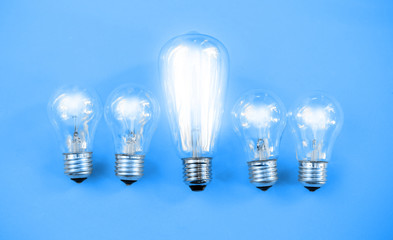 Five bulbs on a blue background and one of them is glowing.