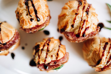Cheese donuts with salami and cucumbers under balsamic sauce. Catering