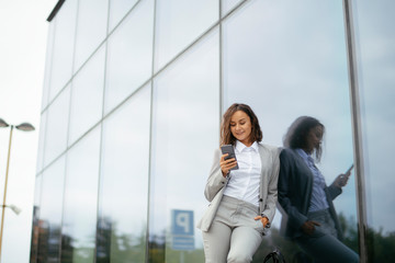 Young businesswoman in suit outdoors. Beautiful woman using phone. 