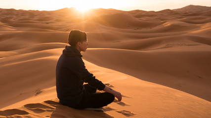 Fototapeta na wymiar man in a desert stares away in the sunrise
