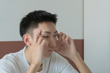 Asian Sad single man lamenting sitting on the bed of an hotel room or home