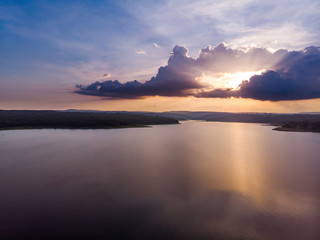 Drone shot aerial view scenic landscape a big river with fresh tree forest and mountain against a sunset sky twilight time