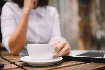 Close up of businesswoman holding cup of coffee and working outdoors. 